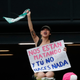 A protester holds a sign reading “They are killing us, and you do nothing”